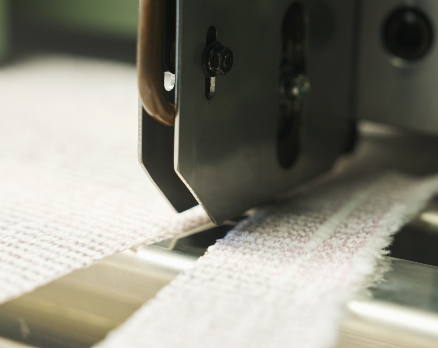 Heat-cutting a woven body towel web to length with sealed fray-free edges