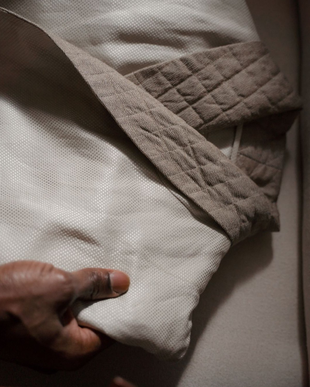 A hand gently holding a soft folded textile