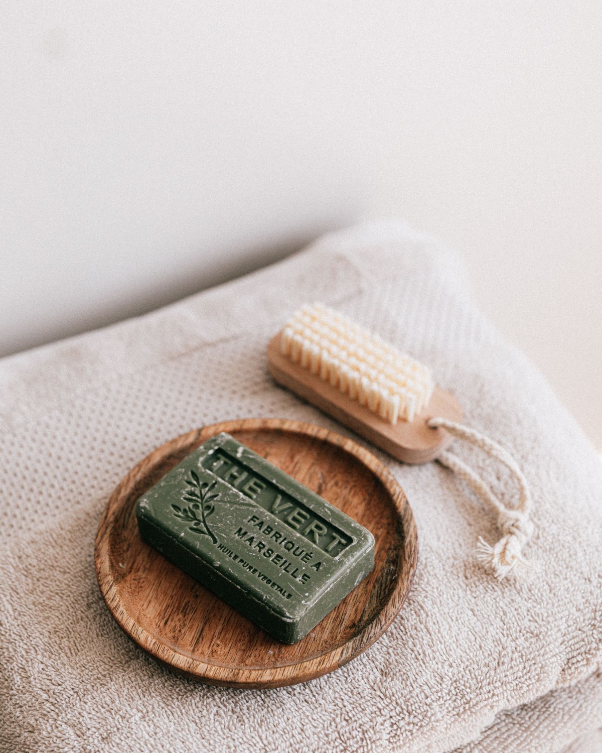 Natural soap and a wooden brush resting on a soft folded towel