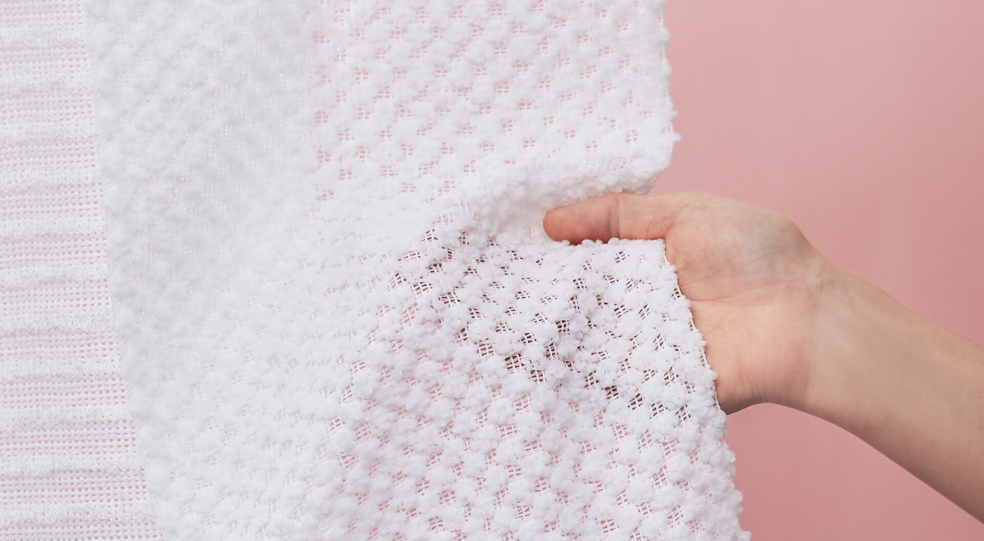 Hand holding a textured Japanese exfoliating body towel made in Japan